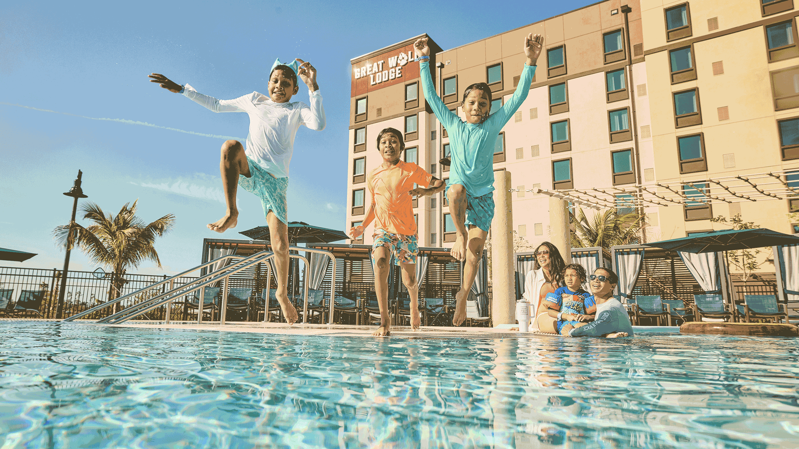 three children jumping into a pool making a splash