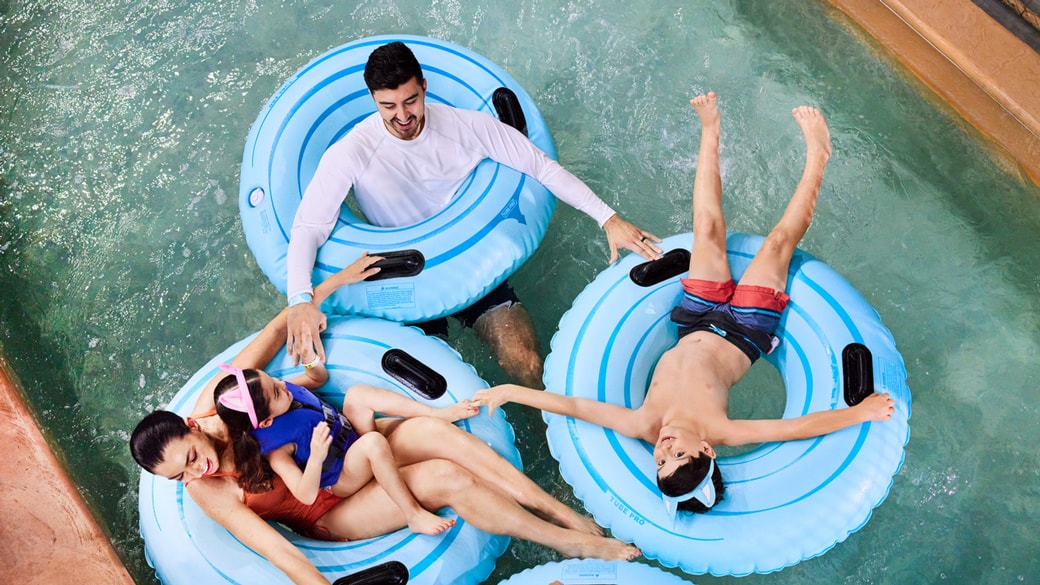 Family floating on a blue float and enjoying indoor waterpark at Great Wolf Lodge