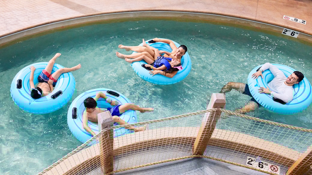 Two boys floating on a yellow and blue tube in the pool at Great Wolf Lodge