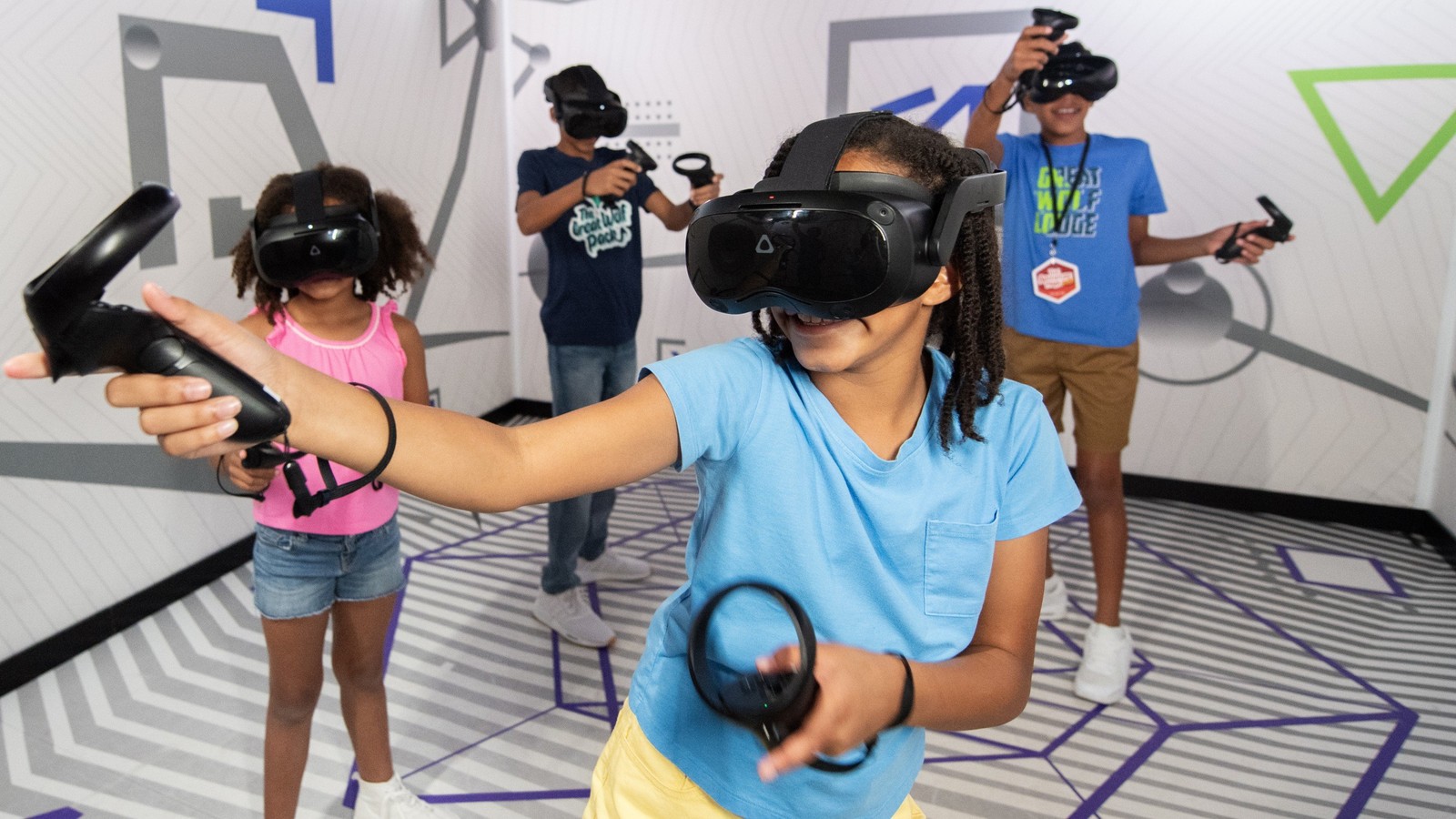 Kids wearing VR headsets play with controllers indoors