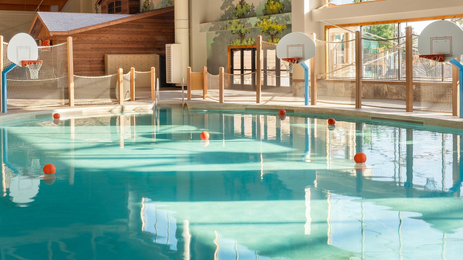 A spacious indoor pool featuring basketball hoops above the water