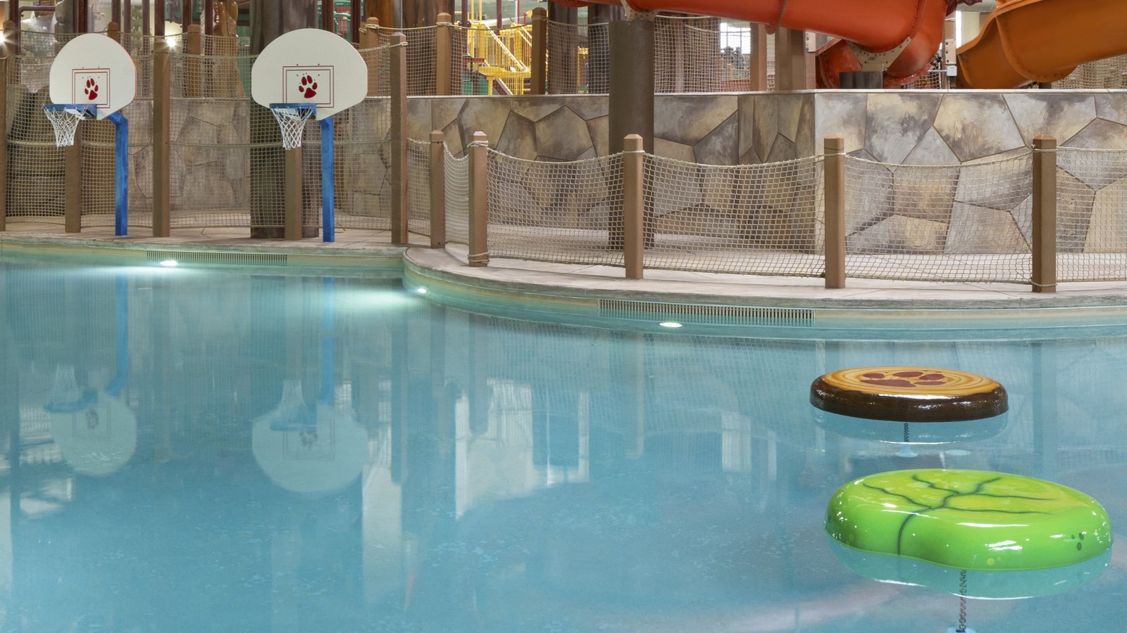 Indoor pool featuring a water slide and a basketball hoop for recreational activities.