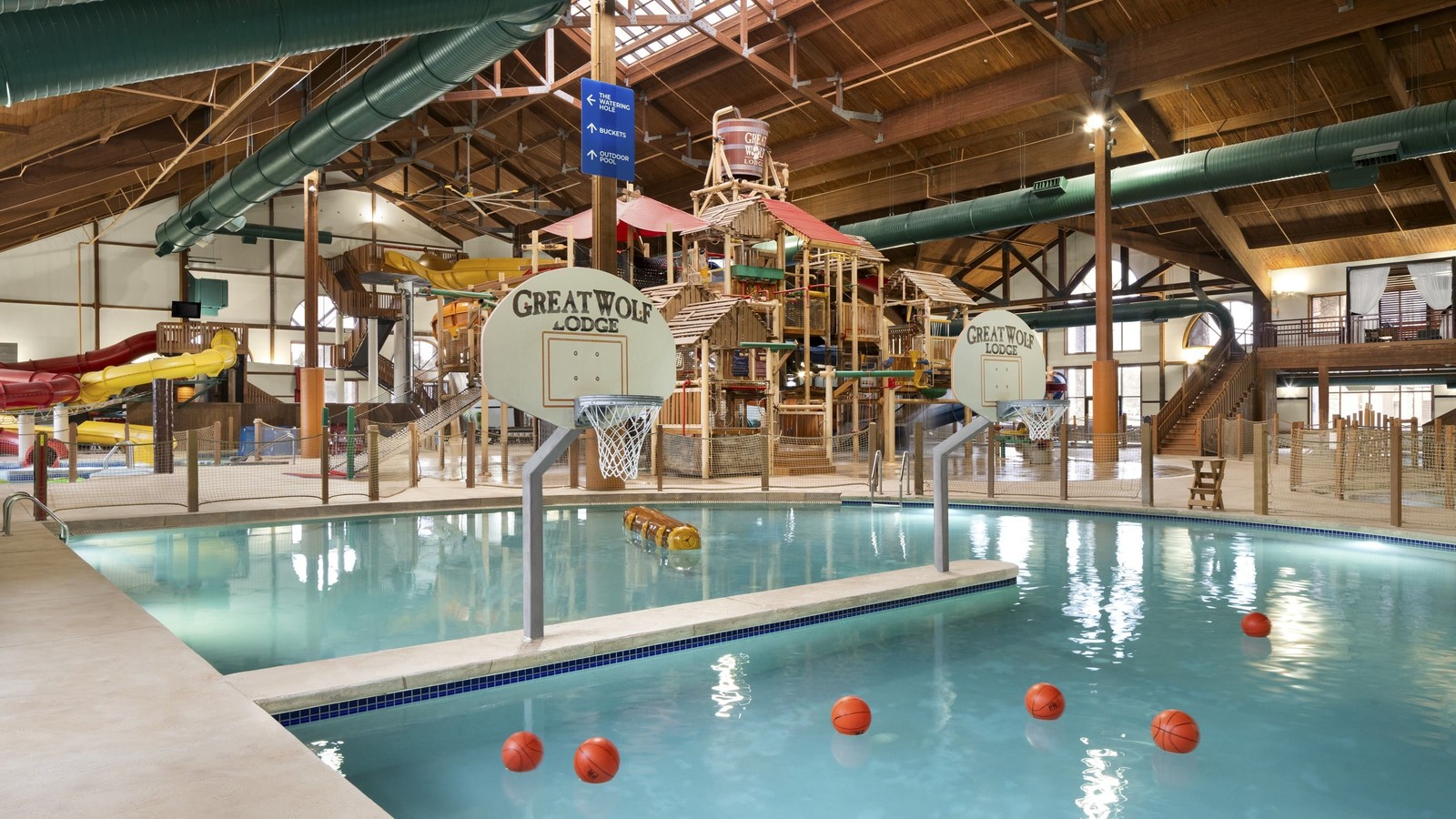 A large indoor water park featuring multiple slides and a basketball hoop for recreational activities.
