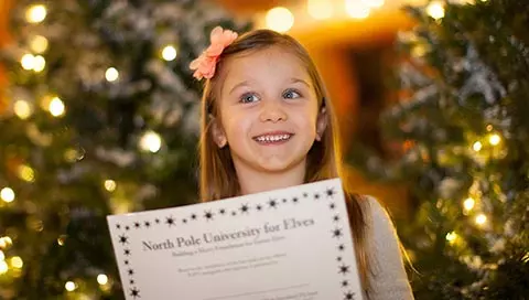 A girl holding a paper smiles as she celebrates the holidays