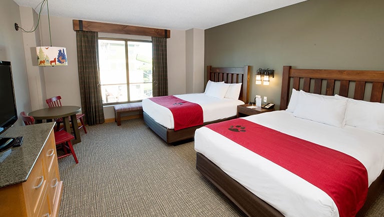 interior of Family Suite with two beds, a window, table and TV on stand