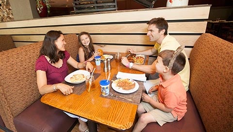 A family of four enjoys breakfast in a their own booth.