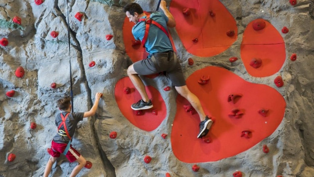 father and son climbing a wall