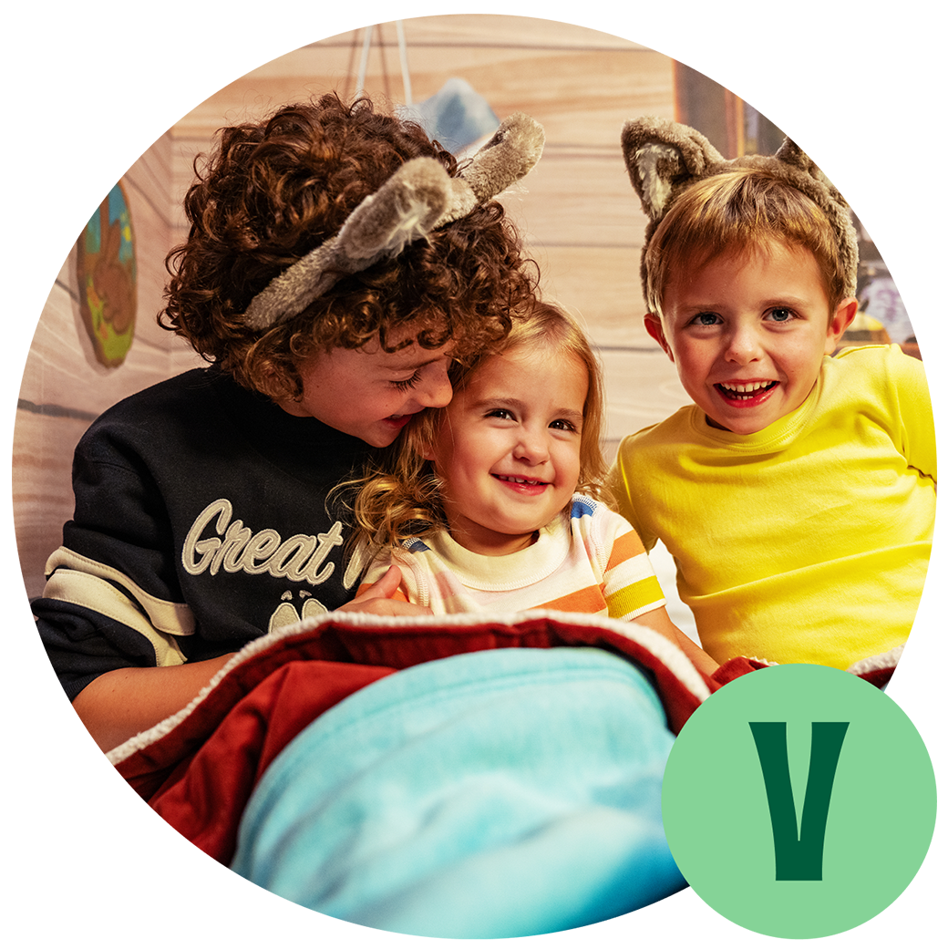 3 kids sitting on a hotel bed and smiling