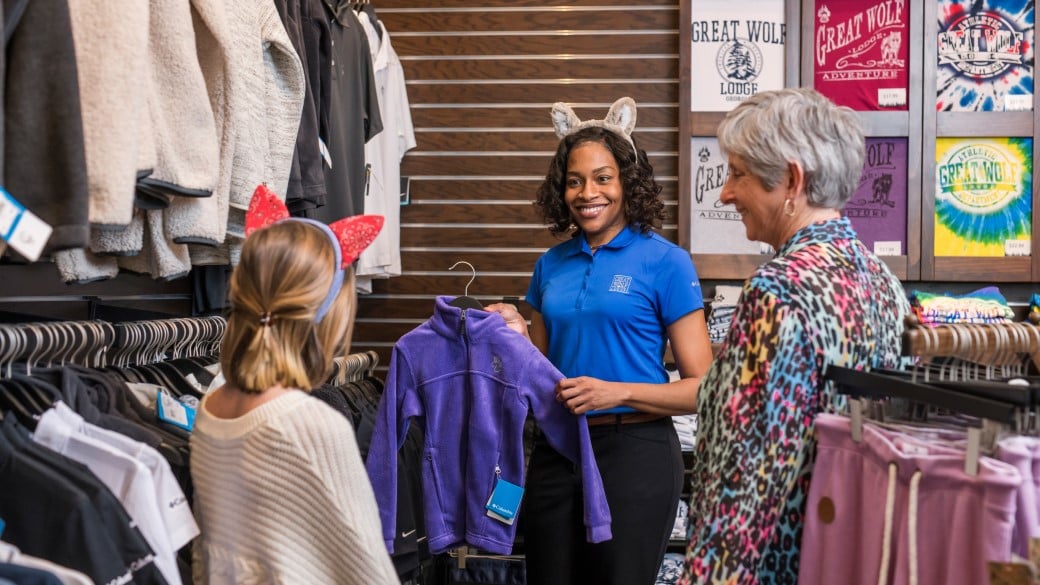 an employee shows sweatshirt to guests at a shopping outlet