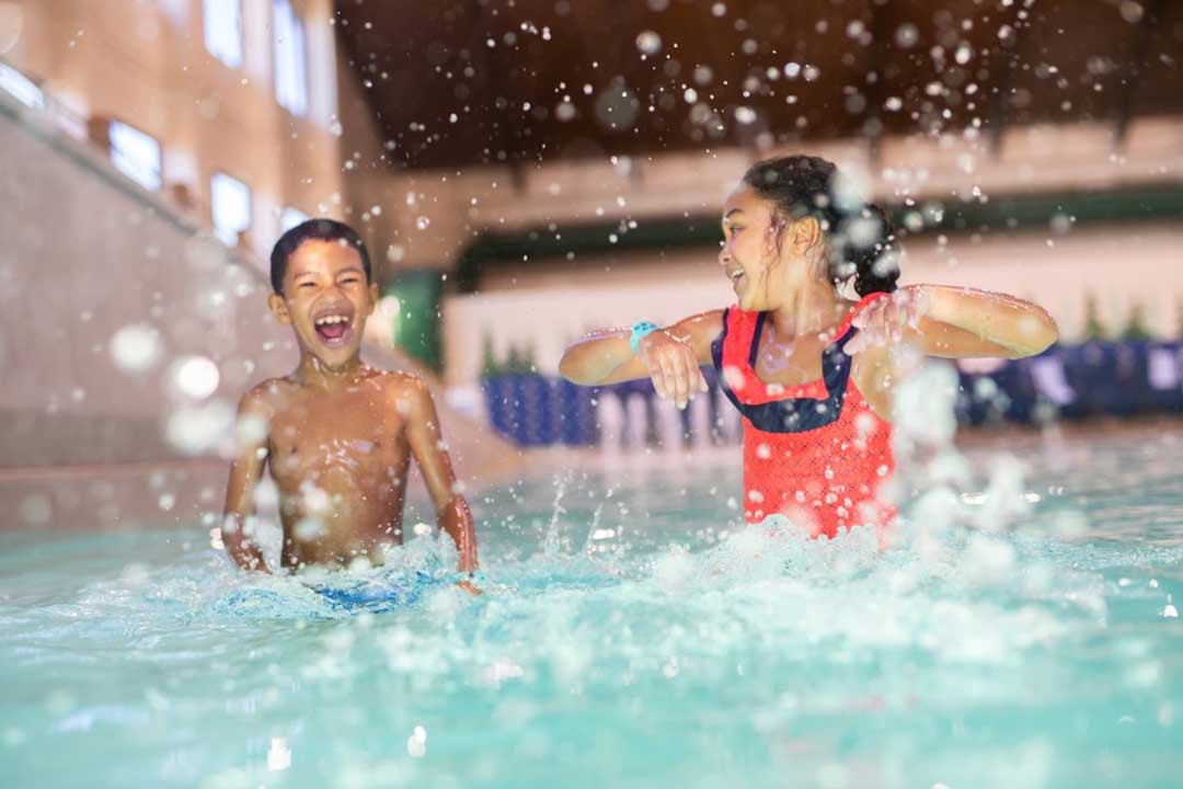 Brother and sister running in a shallow pool  