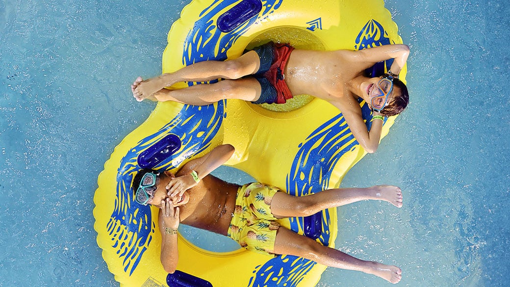 Two boys floating on a yellow and blue tube in the pool at Great Wolf Lodge
