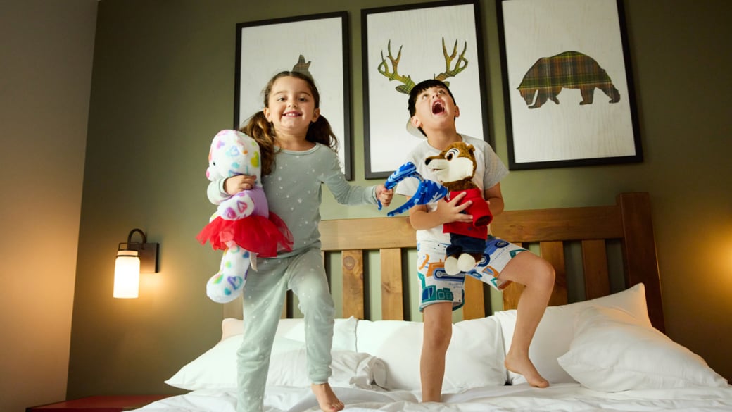 Little girl and brother jumping on a bed at Great Wolf Lodge