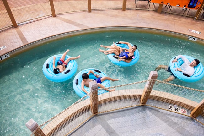 boy wearing swimming glasses and smiling standing under water droplets
