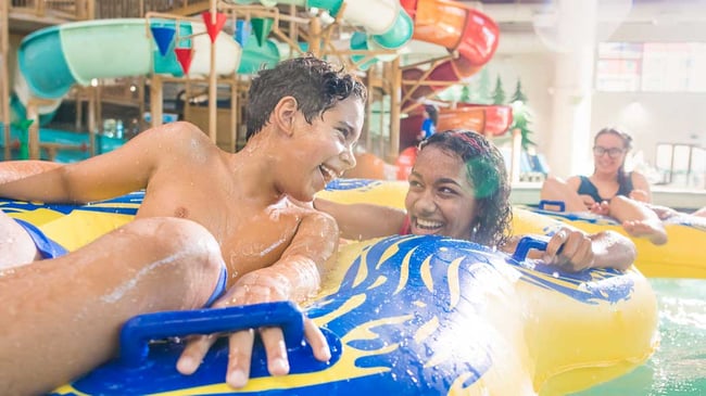 a boy and girl rides a tube in water park