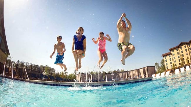 Family jumping into an outdoor pool at Great Wolf Lodge