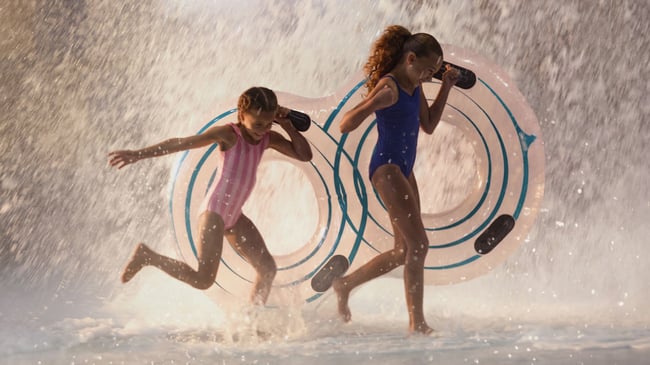 girls holding floating tubes getting soaked in water