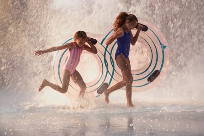 Children playing in water with splash feature and toys.