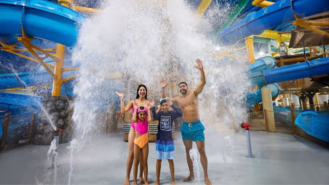 family standing under the water bucket splashing water
