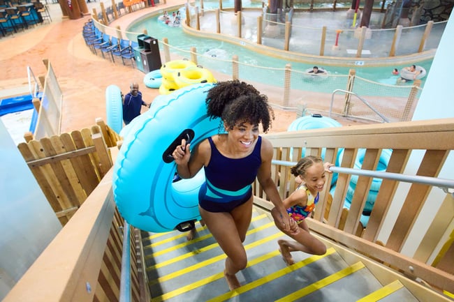 mother and daughter climbing stairs holding a rubber tube feeling happy and exited