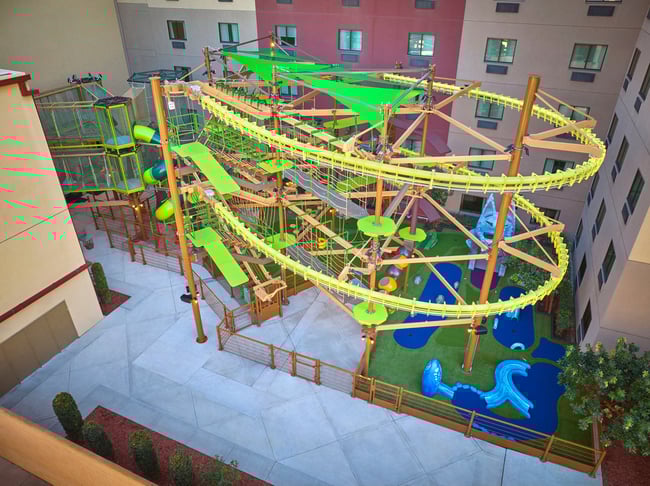 Young girl with a pink shirt navigating indoor ropes course