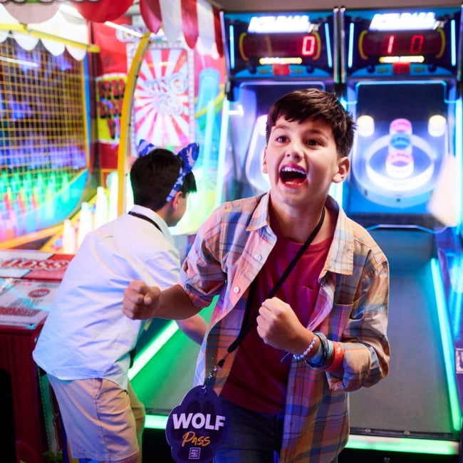 Boy celebrating while playing arcade basketball game