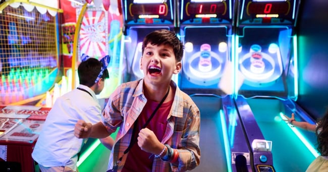 Boy celebrating while playing arcade basketball game