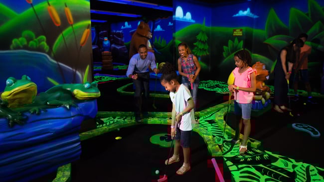 Family watching son play a hole of Glow Golf