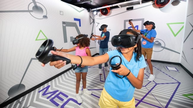 Kids wearing VR headsets play with controllers indoors