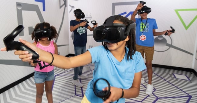 Kids wearing VR headsets play with controllers indoors