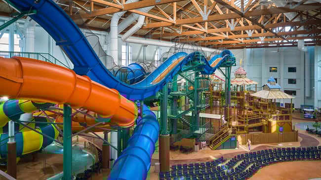 view of the indoor water park with a yellow and blue slide 