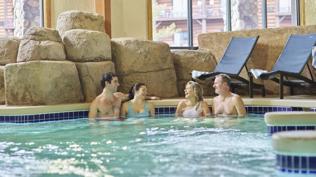 Two couples relax in an indoor hot tub