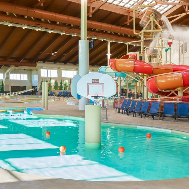 family playing basketball in indoor pool 