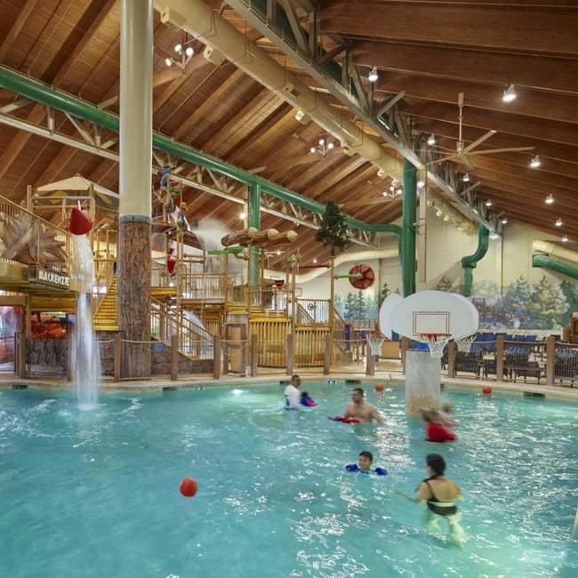 family playing basketball in indoor pool 