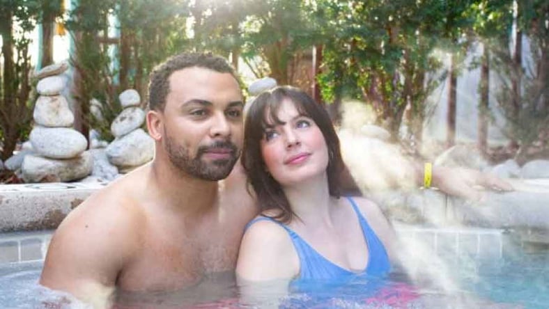 A couple relax by the outdoor whirlpool spa at Great Wolf Lodge indoor water park and resort.