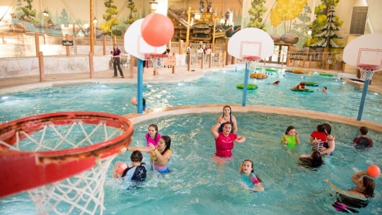 family playing basketball in indoor pool 