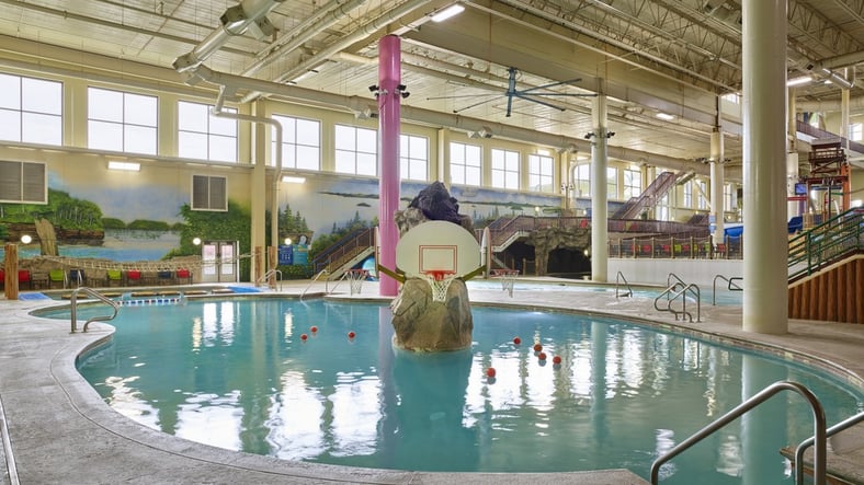 family playing basketball in indoor pool 