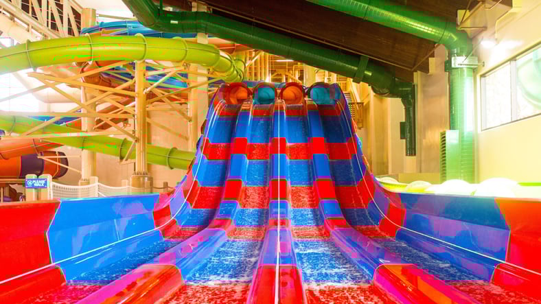Two kids race down a waterslide laying on their stomaches 