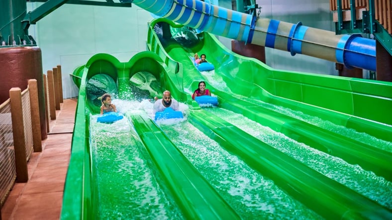 Guests race down a waterslide laying on their stomaches 
