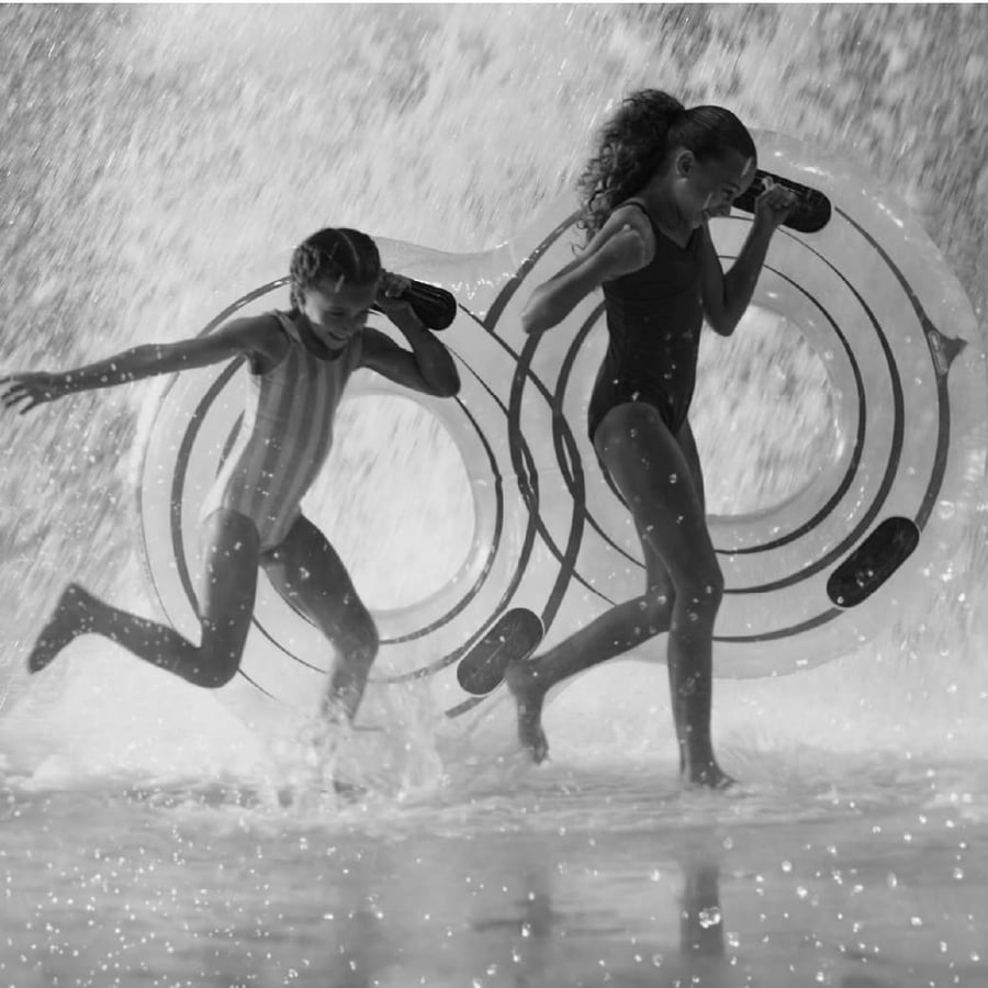 2 girls carrying water tubes getting soaked in water