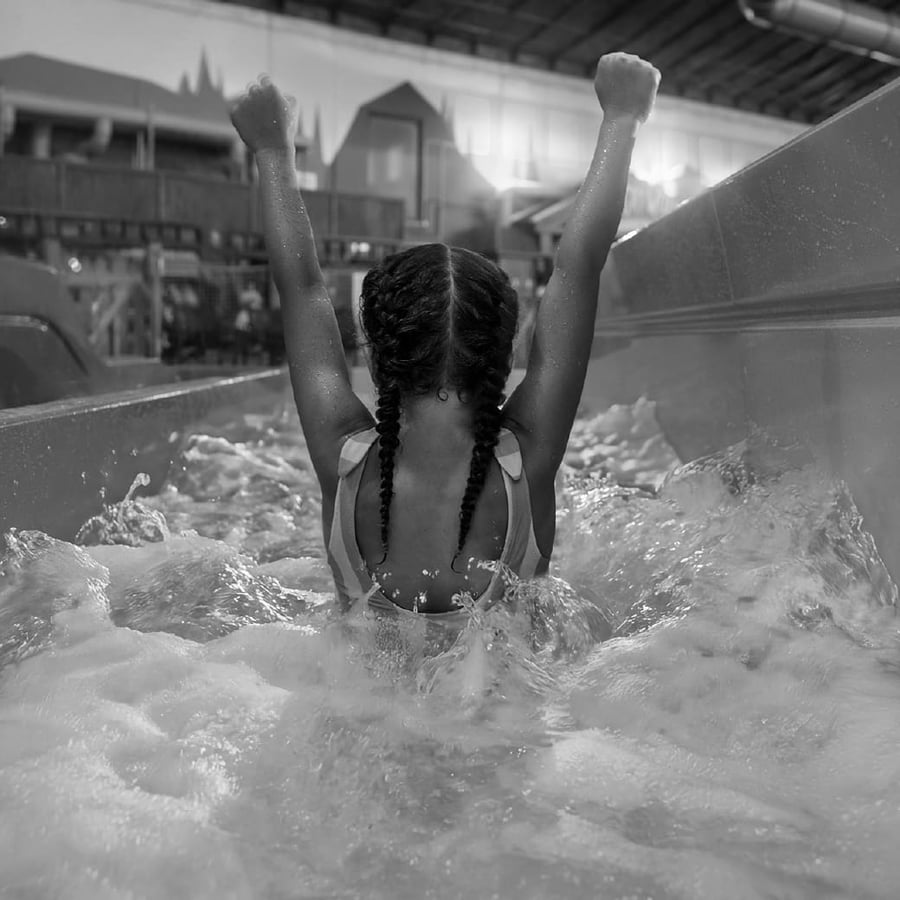 a girl with her hands in the air as she starts to go down a water slide