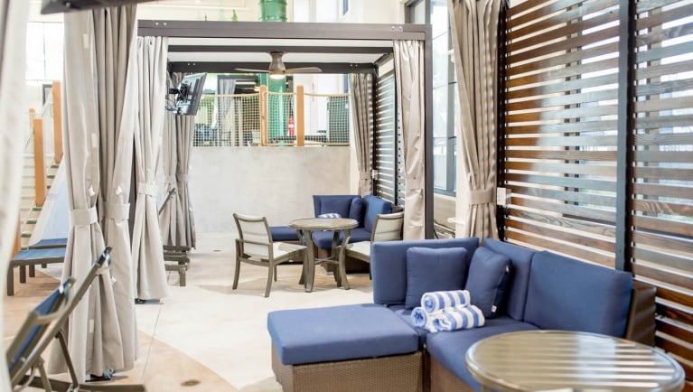 tables, chairs and blue couches in the cabana area