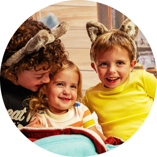 3 kids sitting on a hotel bed and smiling