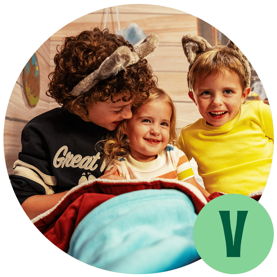 3 kids sitting on a hotel bed and smiling