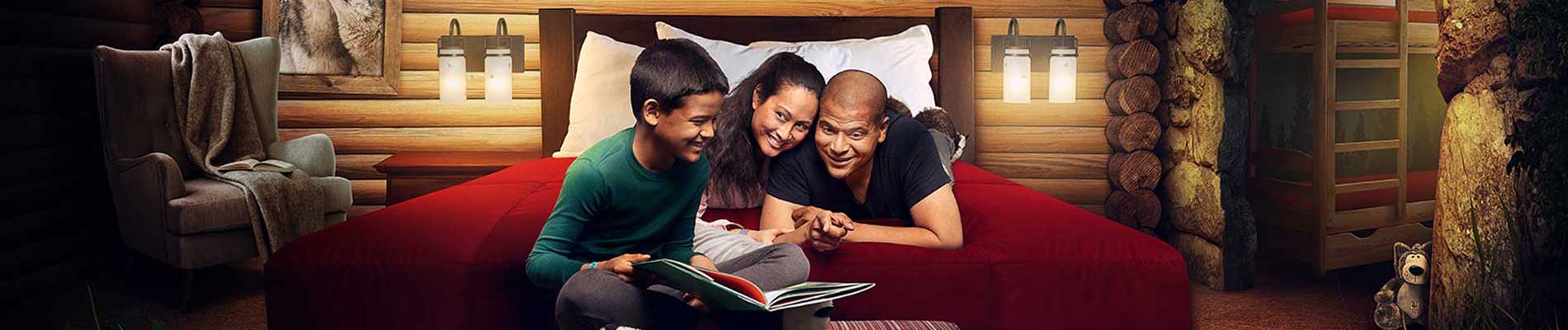 A family of three reading a book on a queen bed