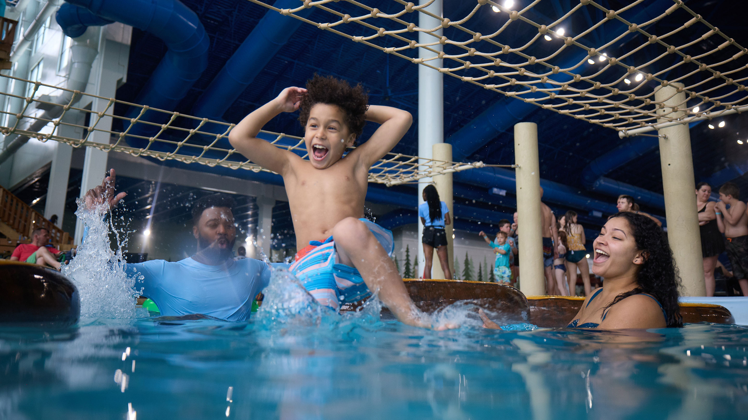 boy having fun in a pool with his parents