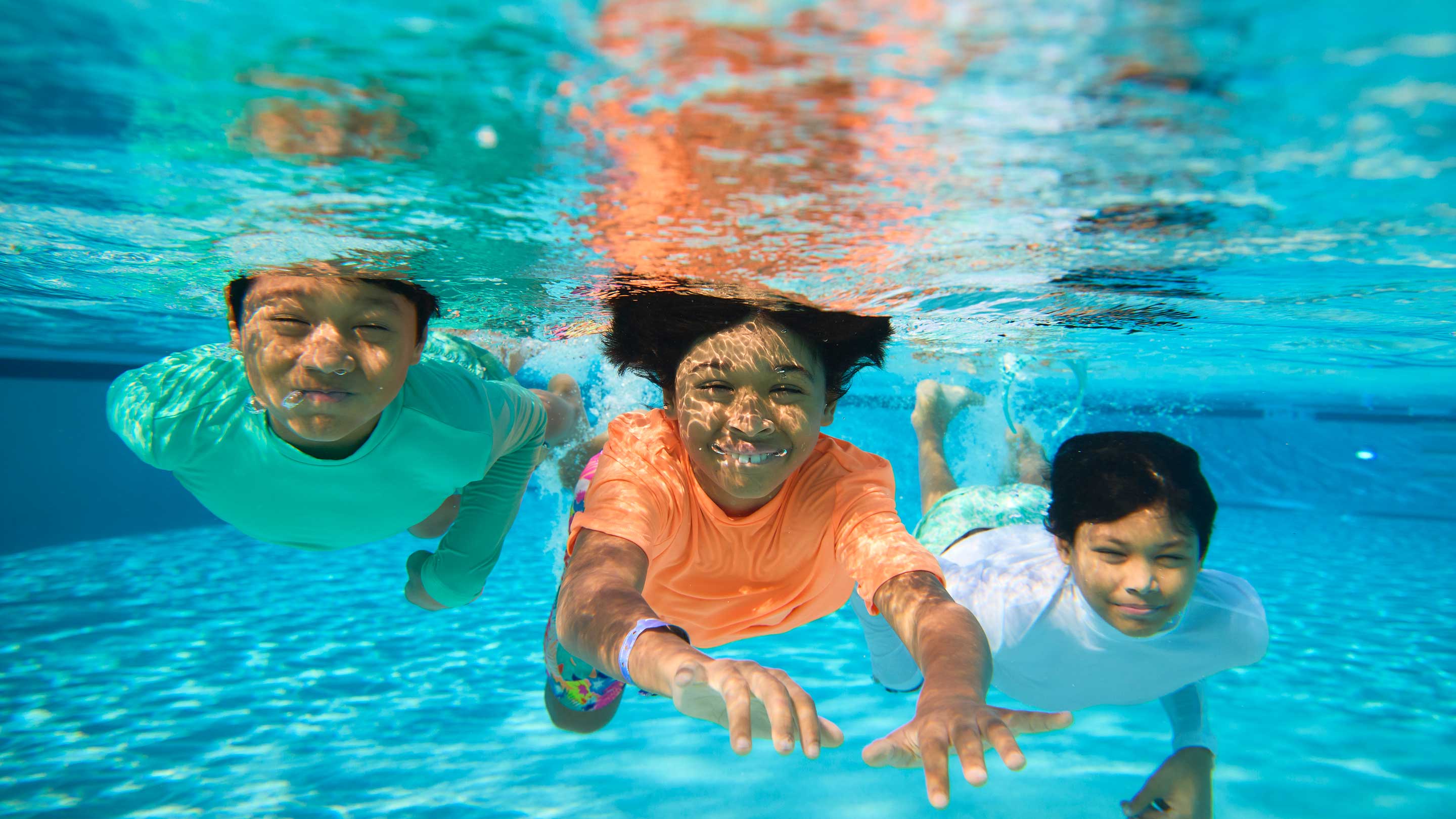 three kids enjoy a dip in the pool