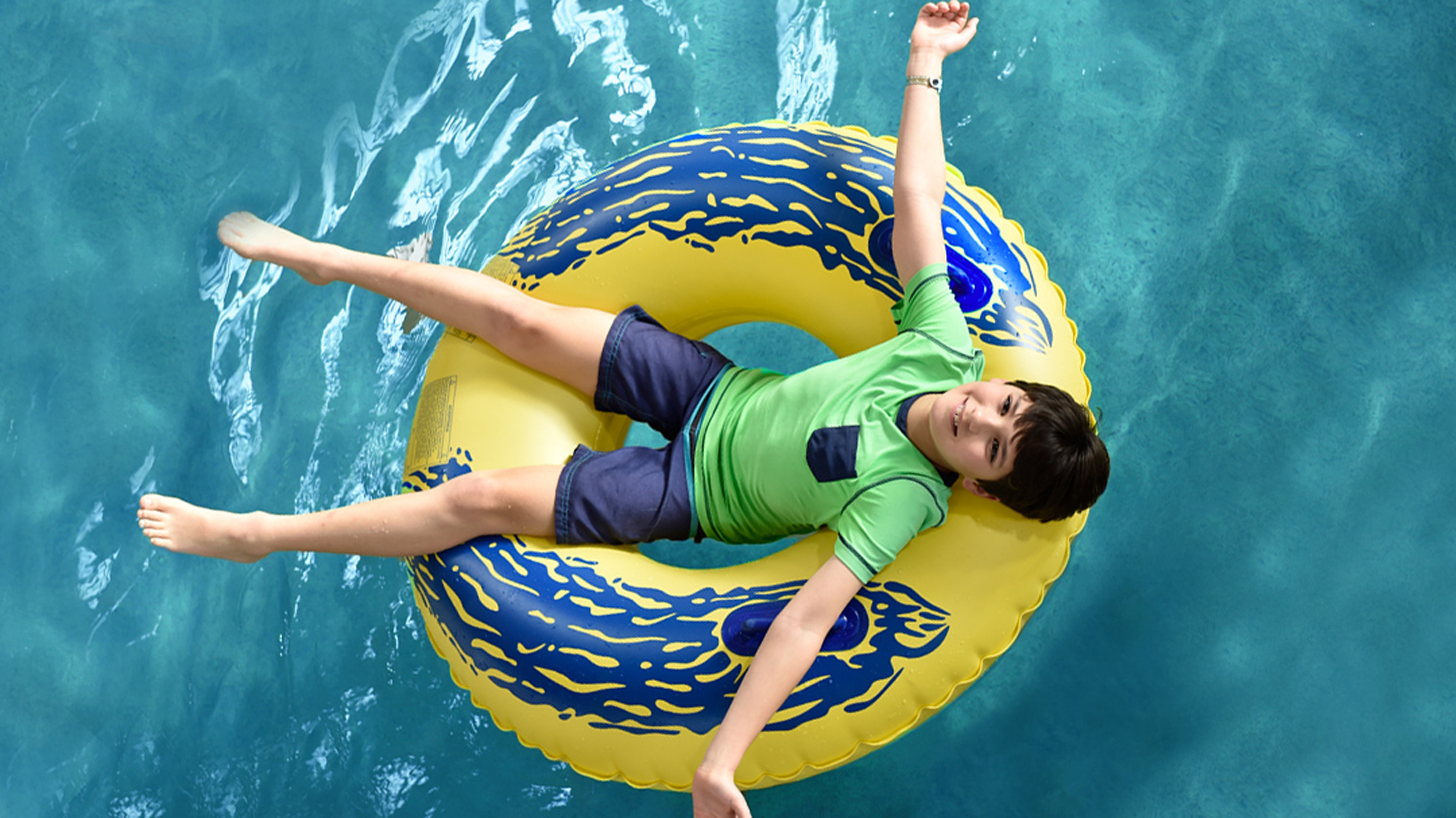 a young boy floating by himself on a green float at Great Wolf Lodge