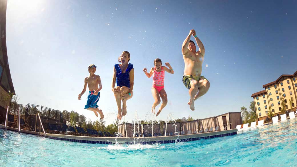 Family jumping into an outdoor pool at Great Wolf Lodge