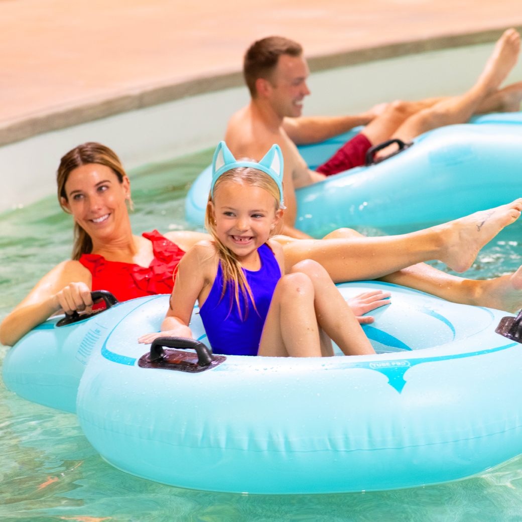 family floating in lazy river water ride using tubes