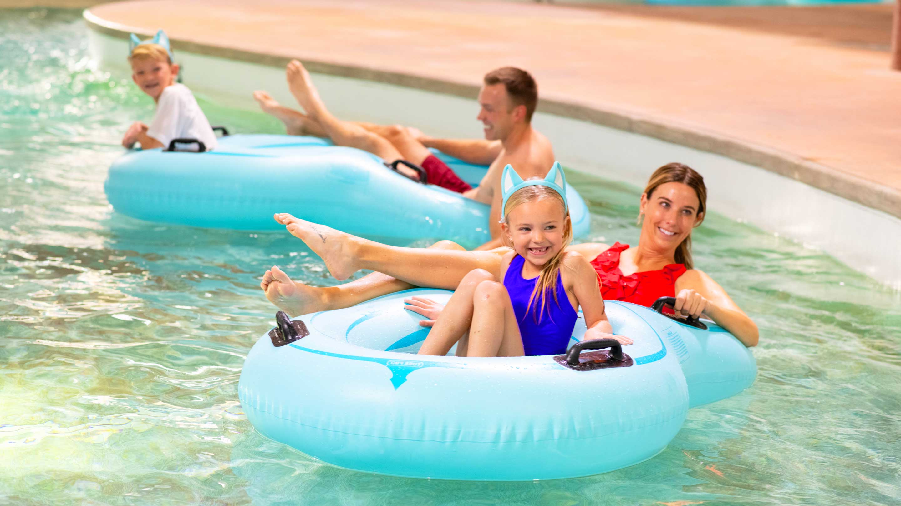 family floating in lazy river water ride using tubes
